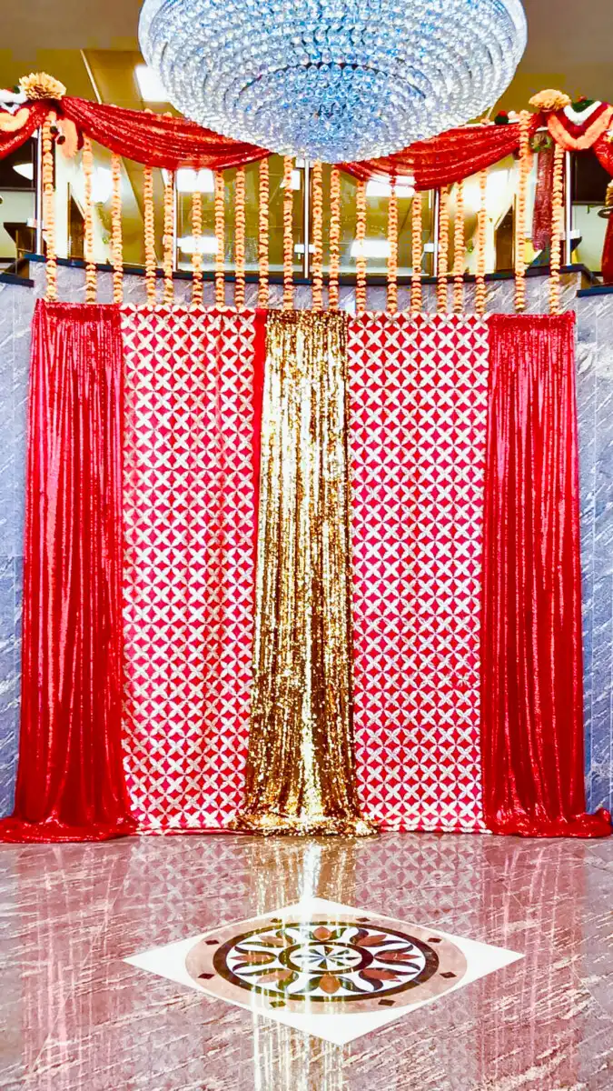Red and gold backdrop with marigold garlands · Dream Decorators