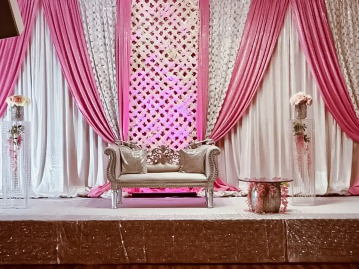 Pink lattice reception stage with silver loveseat · Dream Decorators