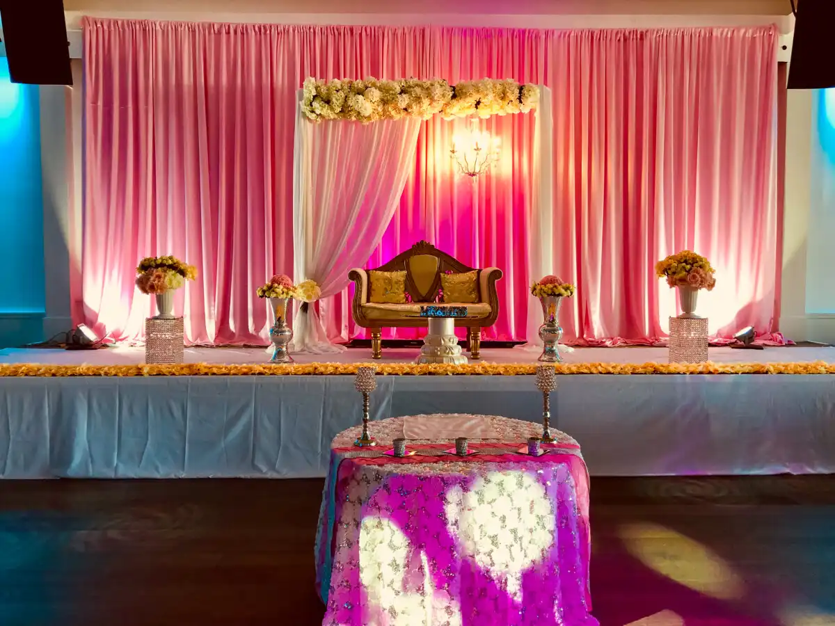 Pink pleated reception stage with floral canopy · Dream Decorators