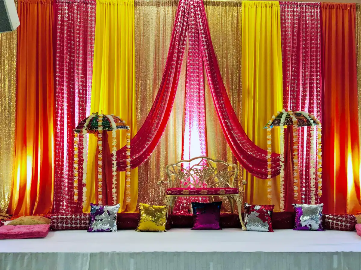 Colourful sangeet stage with gold loveseat · Dream Decorators