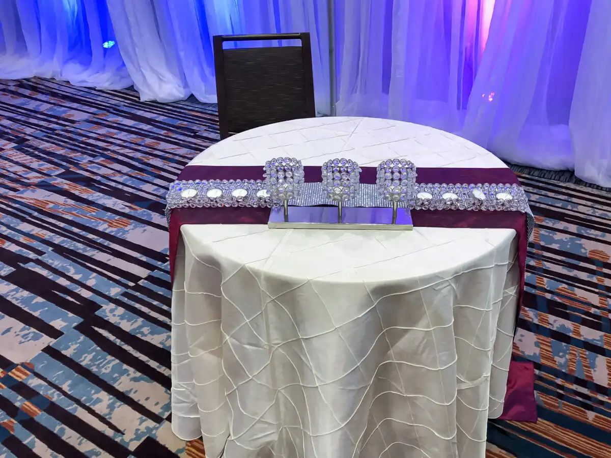 Purple runner sweetheart table with crystal centerpiece · Dream Decorators