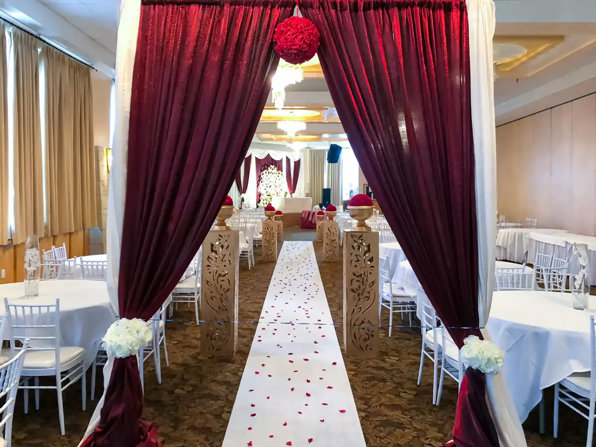 Red and gold wedding aisle entrance with floral pillars · Dream Decorators