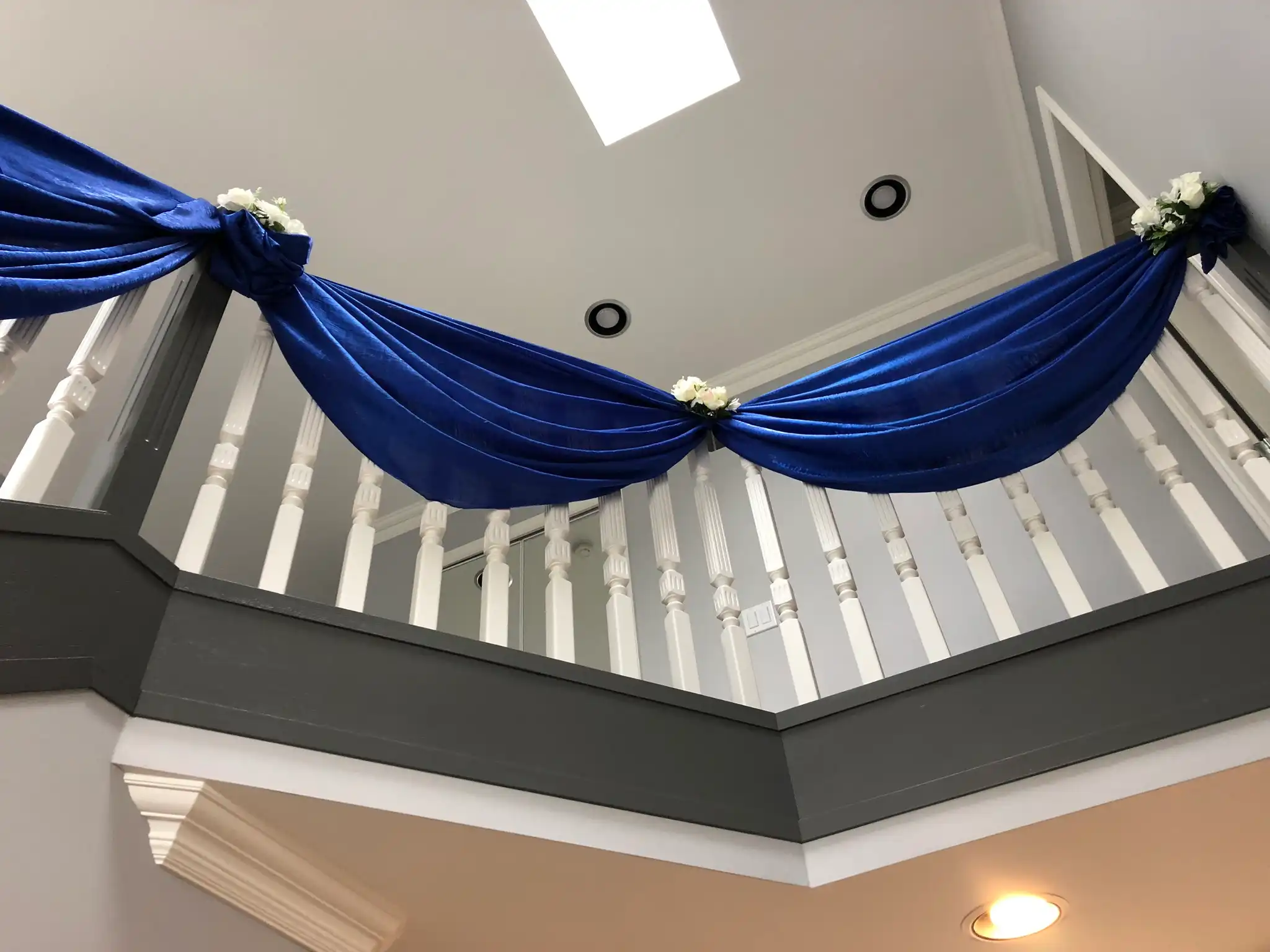 Royal blue fabric swags on home staircase railing · Dream Decorators