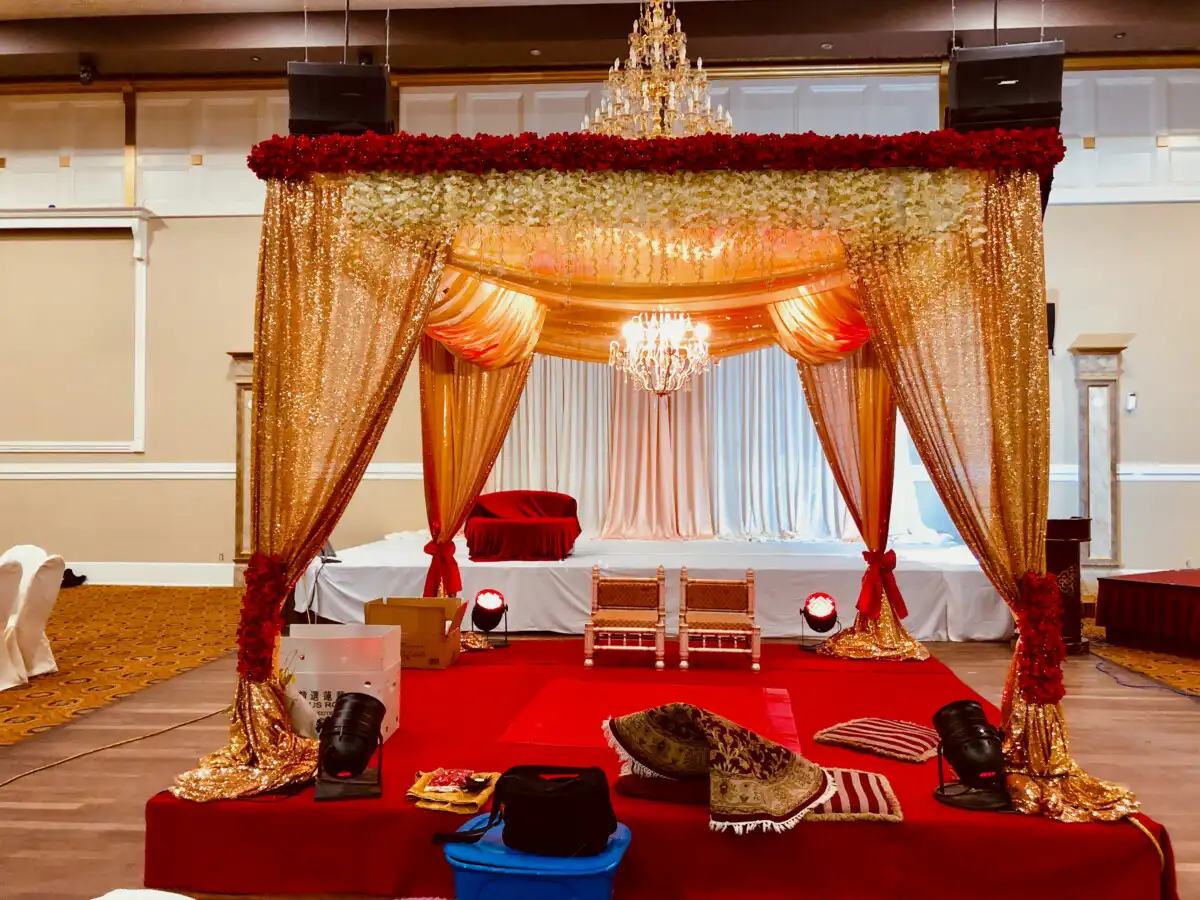 Gold sequin mandap with red roses and chandelier · Surrey wedding décor by Dream Decorators