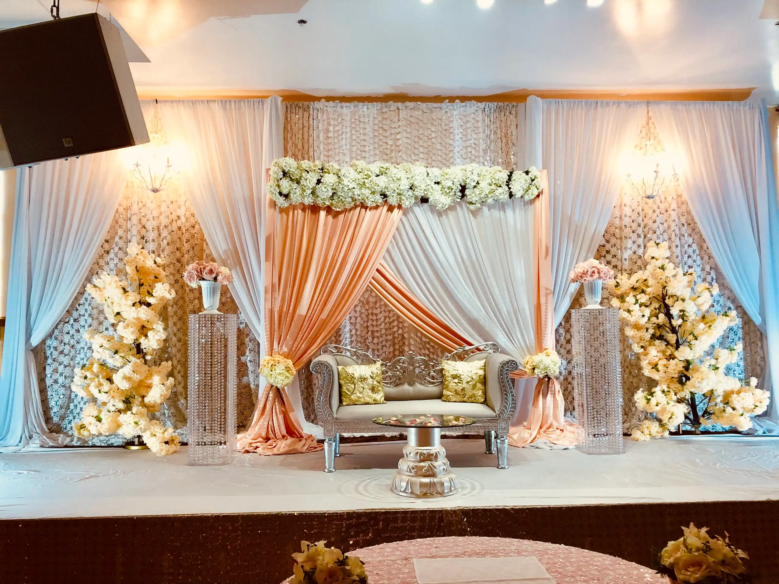 Peach and white reception stage with blossom trees · Dream Decorators