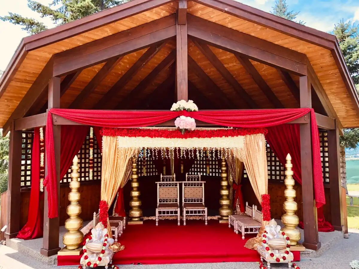Red and gold outdoor mandap in wooden gazebo · Dream Decorators