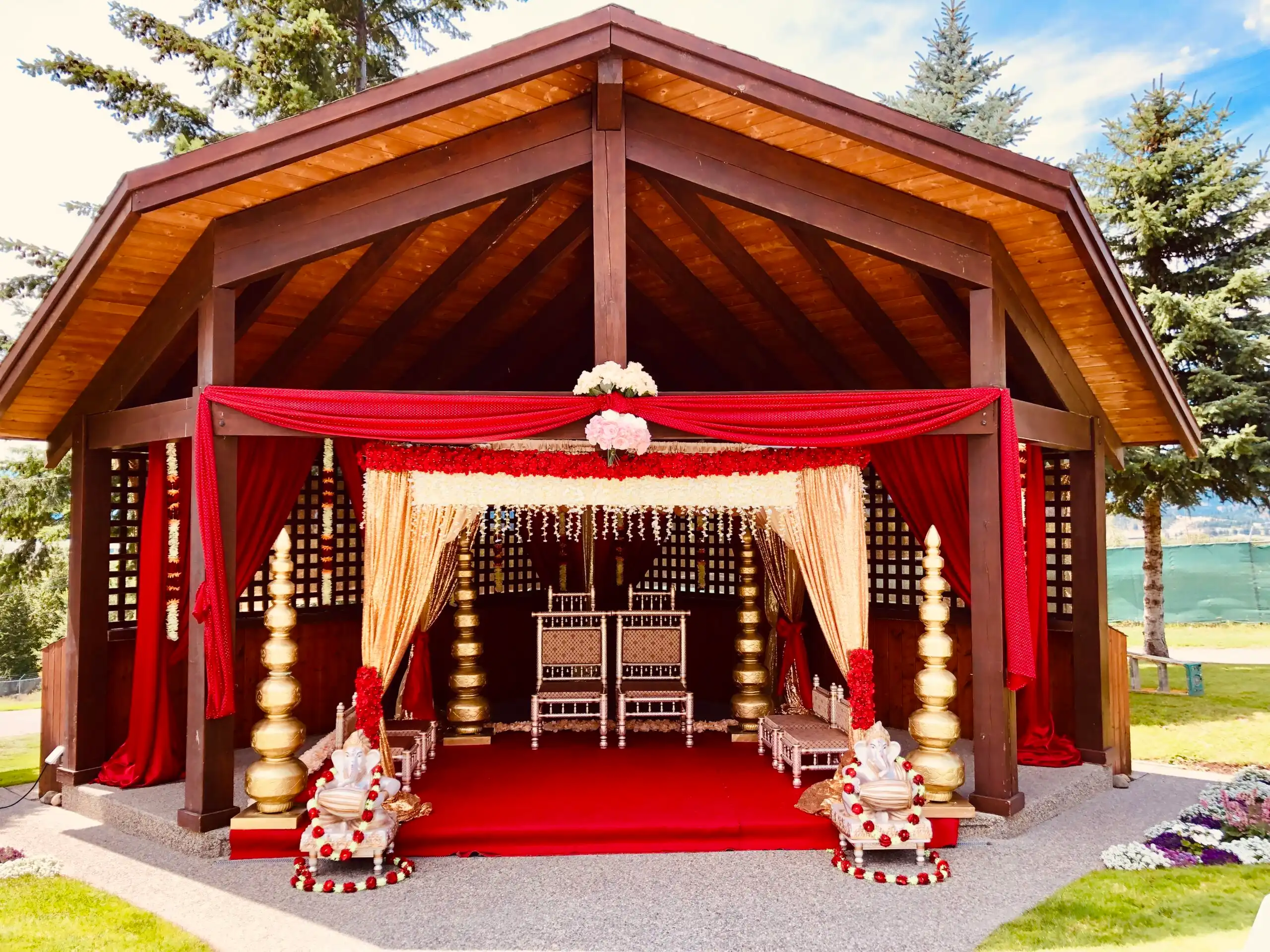 Outdoor red and gold Hindu mandap in wooden pavilion · Dream Decorators