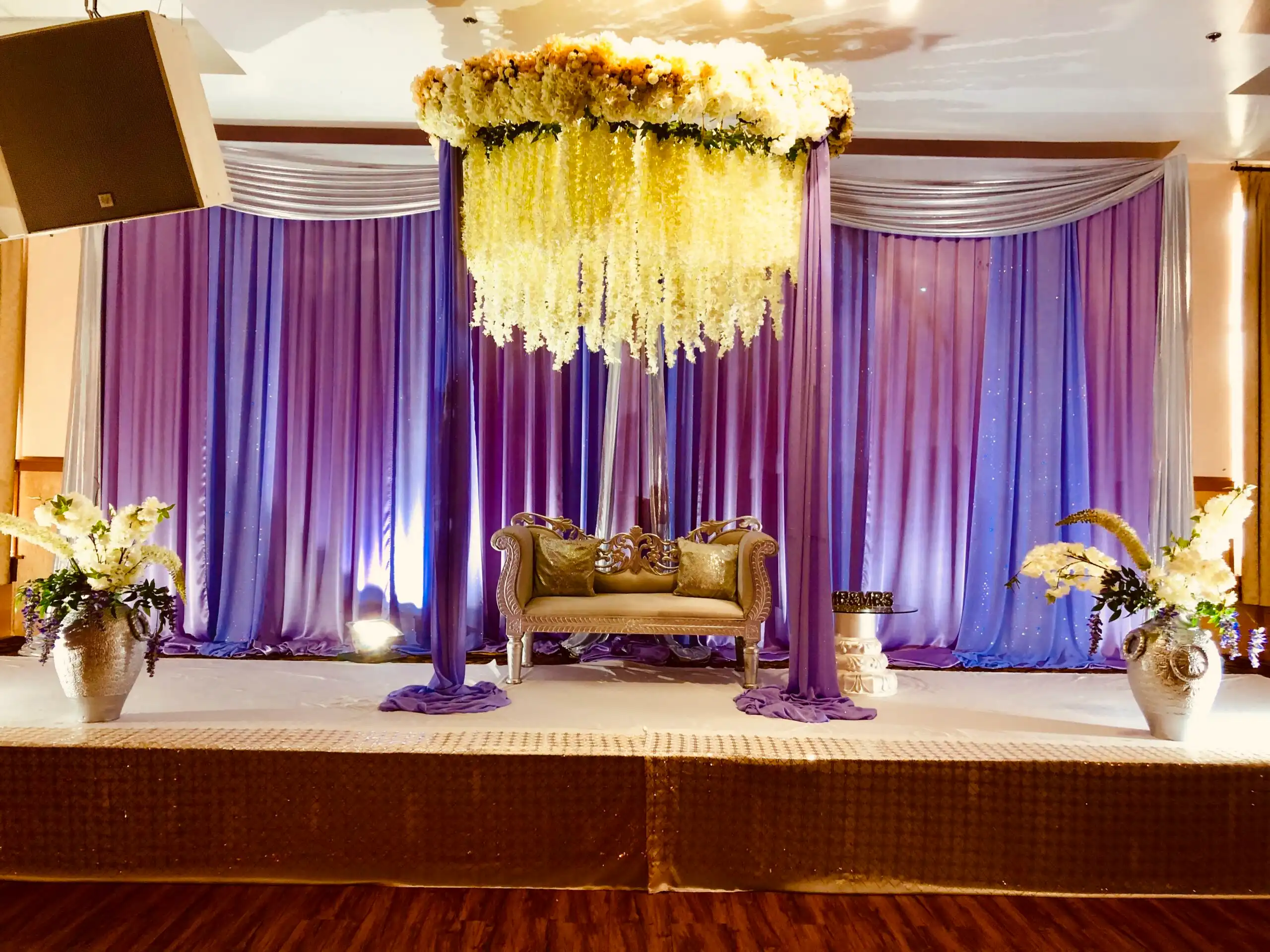 Purple reception stage with floral chandelier and wisteria · Dream Decorators