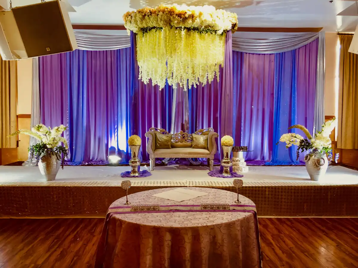 Purple reception stage with cascading floral chandelier · Dream Decorators