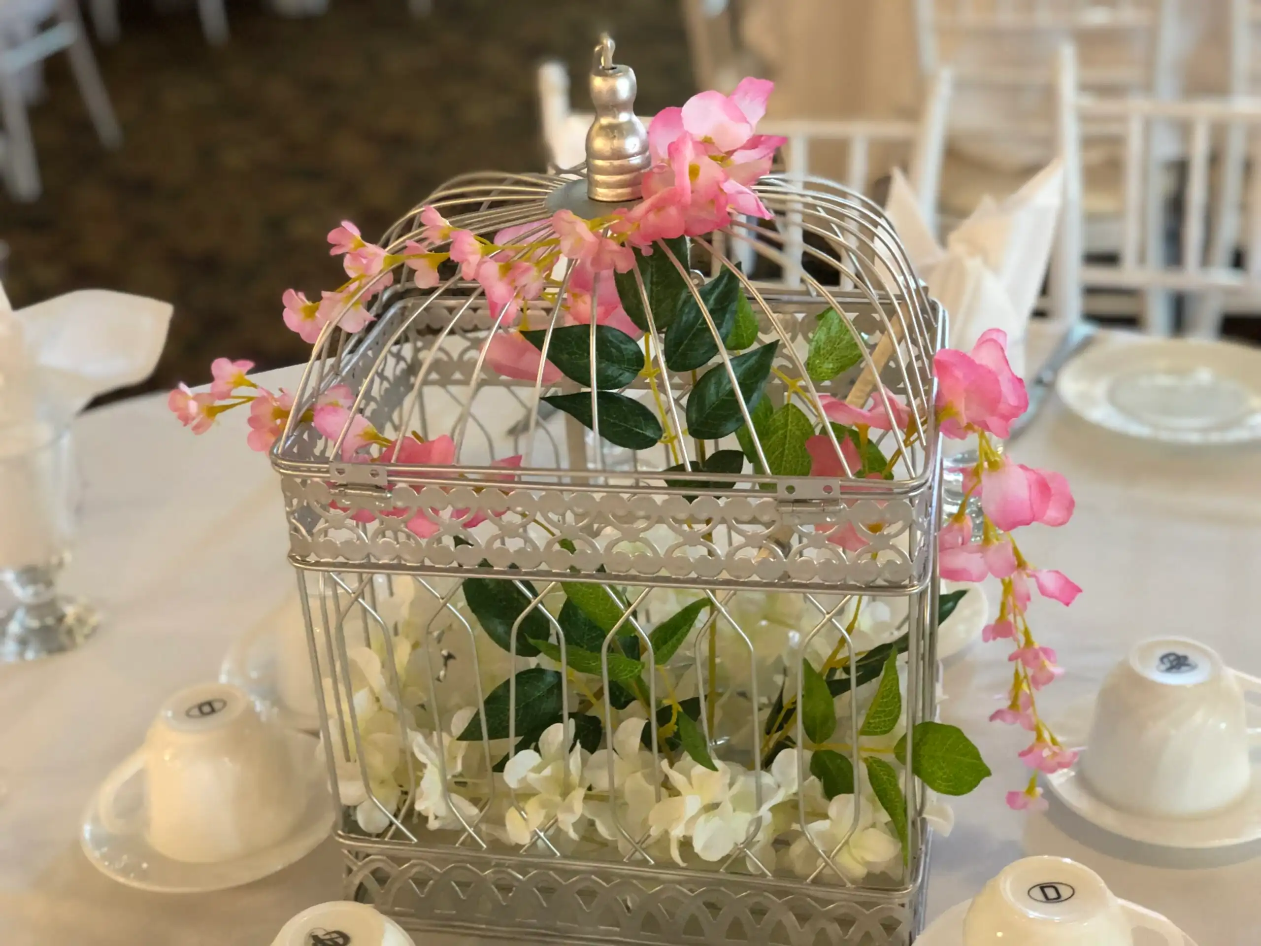 Silver birdcage floral centerpiece with pink blossoms · Dream Decorators