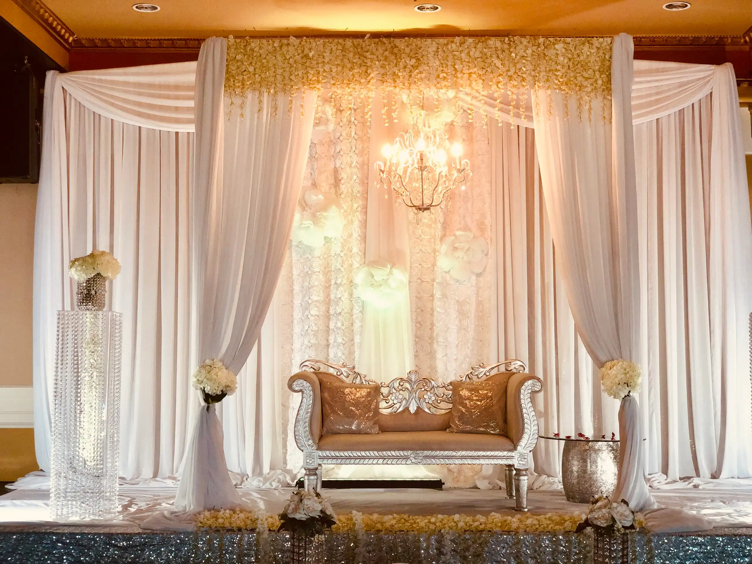 White and silver floral reception stage with chandelier · Dream Decorators
