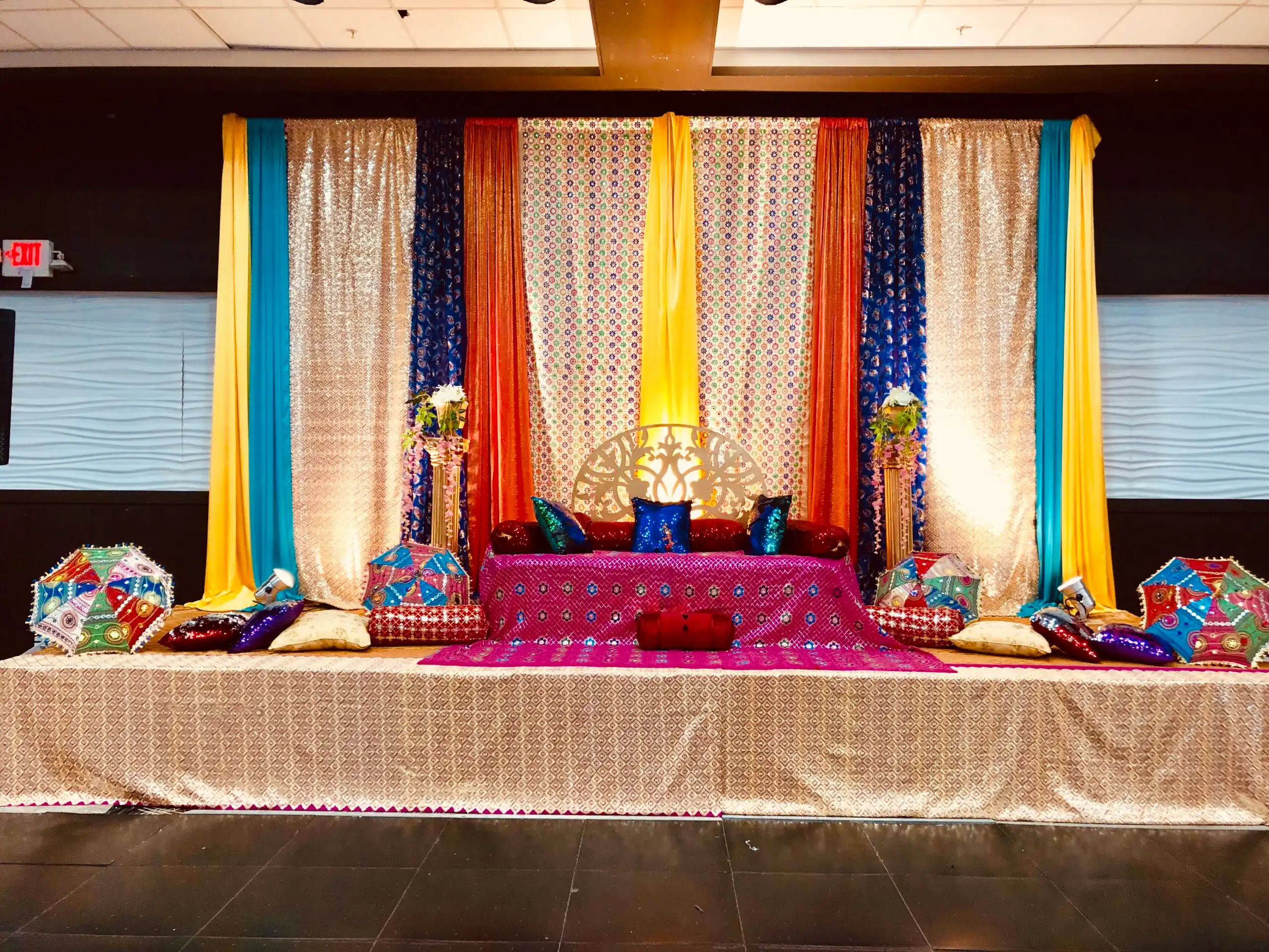 Colorful mehndi stage with embroidered umbrellas · Dream Decorators
