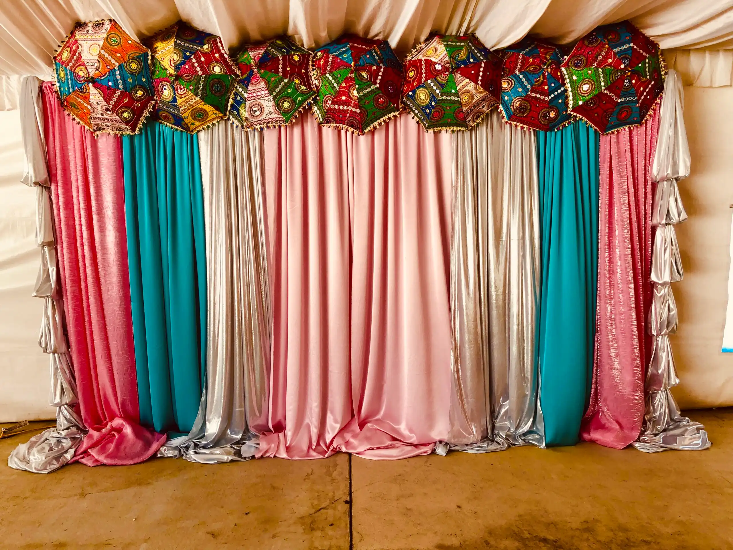 Pink and teal mehndi backdrop with traditional umbrellas · Dream Decorators