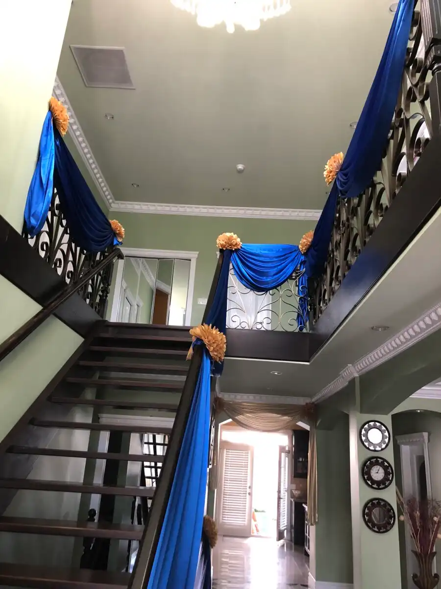 Royal blue home staircase draping with gold rosettes · Dream Decorators