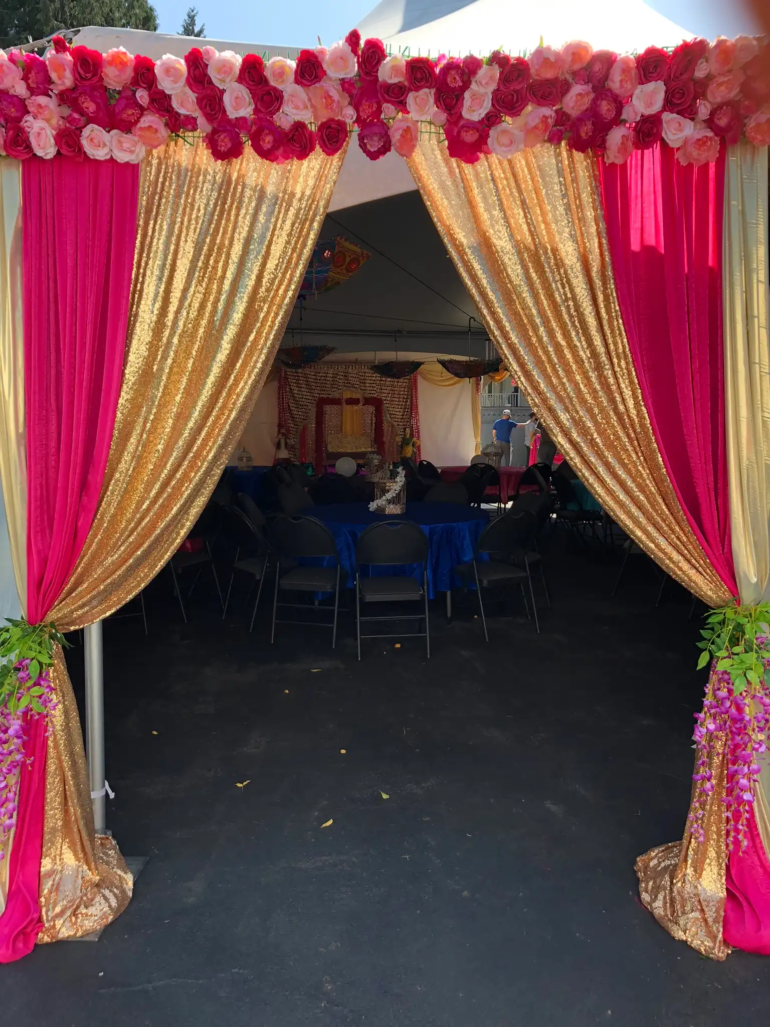 Pink and gold outdoor tent entrance with rose garland · Dream Decorators