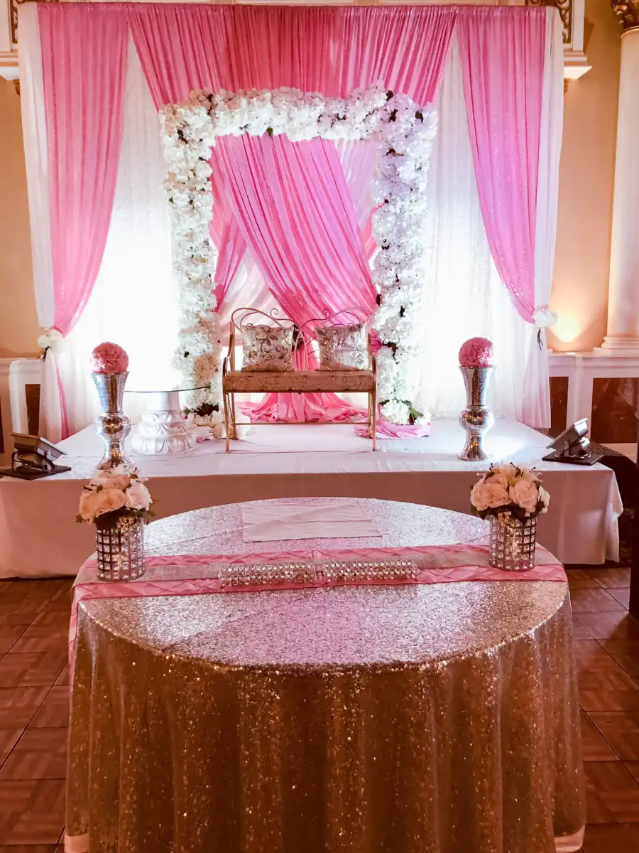 Pink and gold stage with white floral arch · Dream Decorators