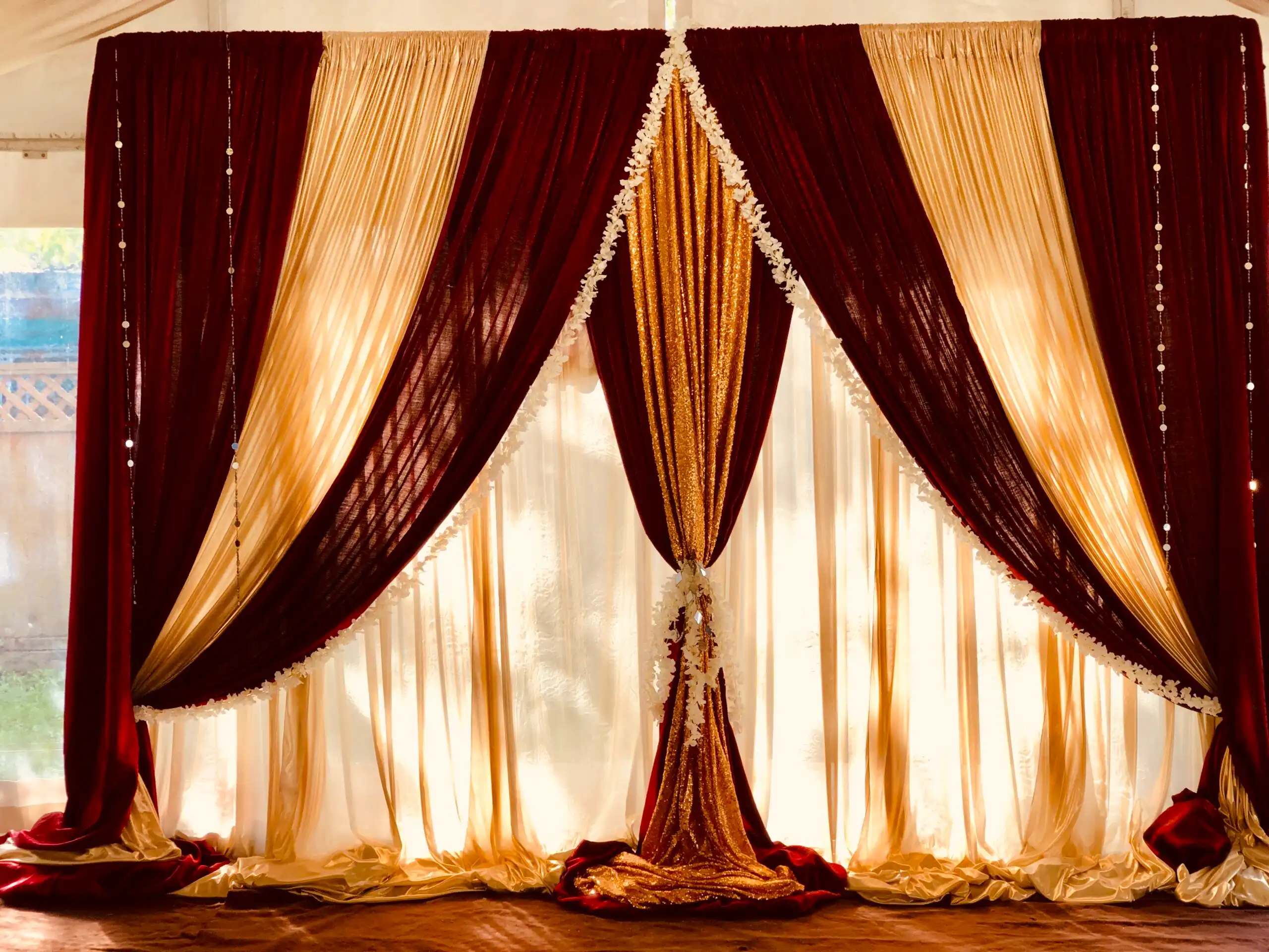 Maroon and gold home ceremony draped backdrop · Dream Decorators