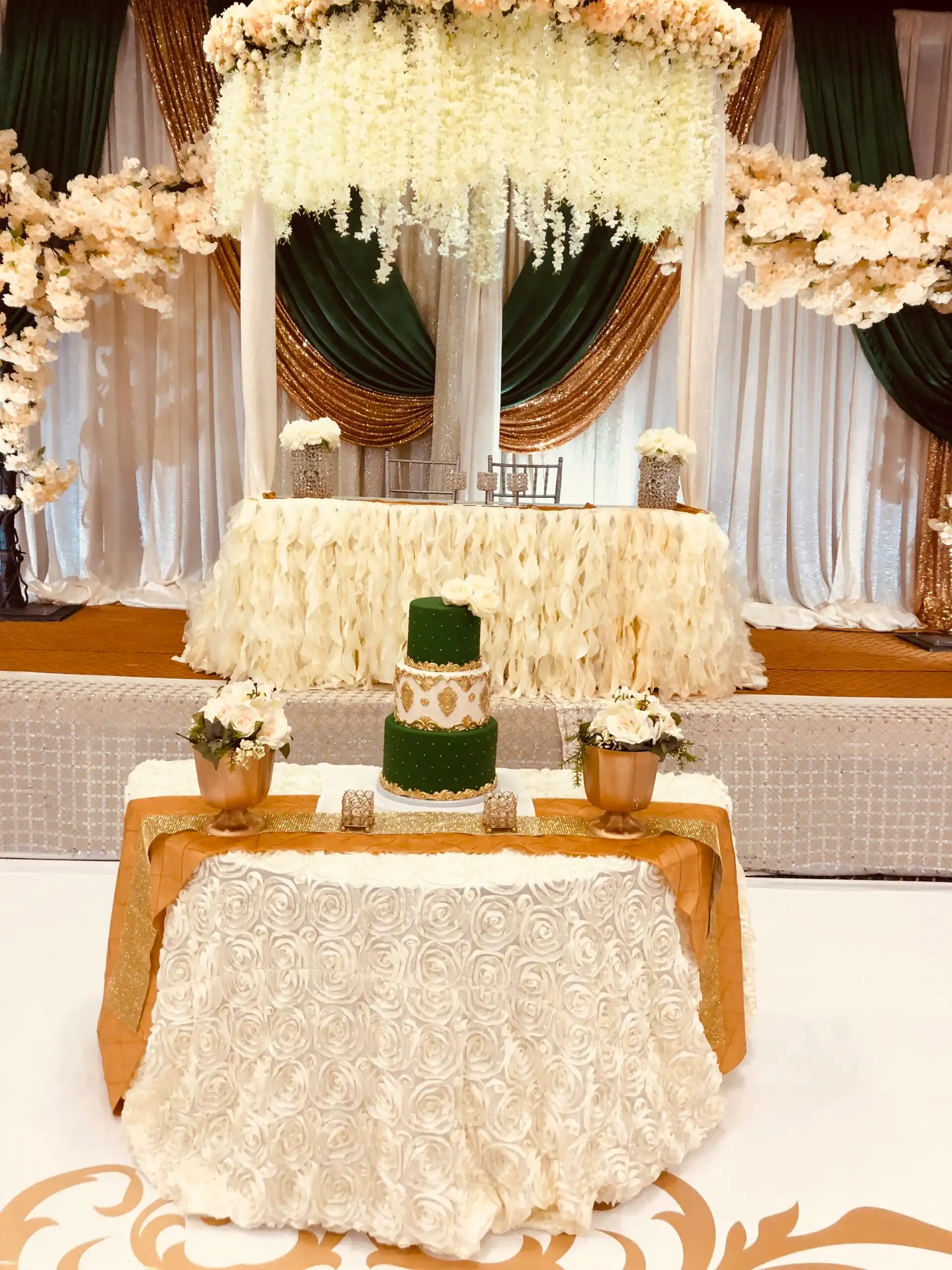 Emerald and gold reception stage with wedding cake · Dream Decorators