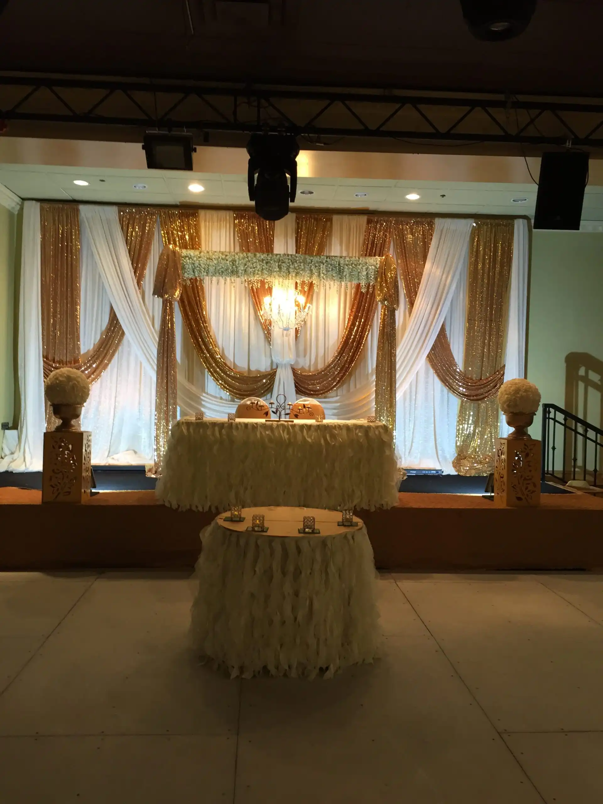 Gold and white reception stage with crystal chandelier · Dream Decorators