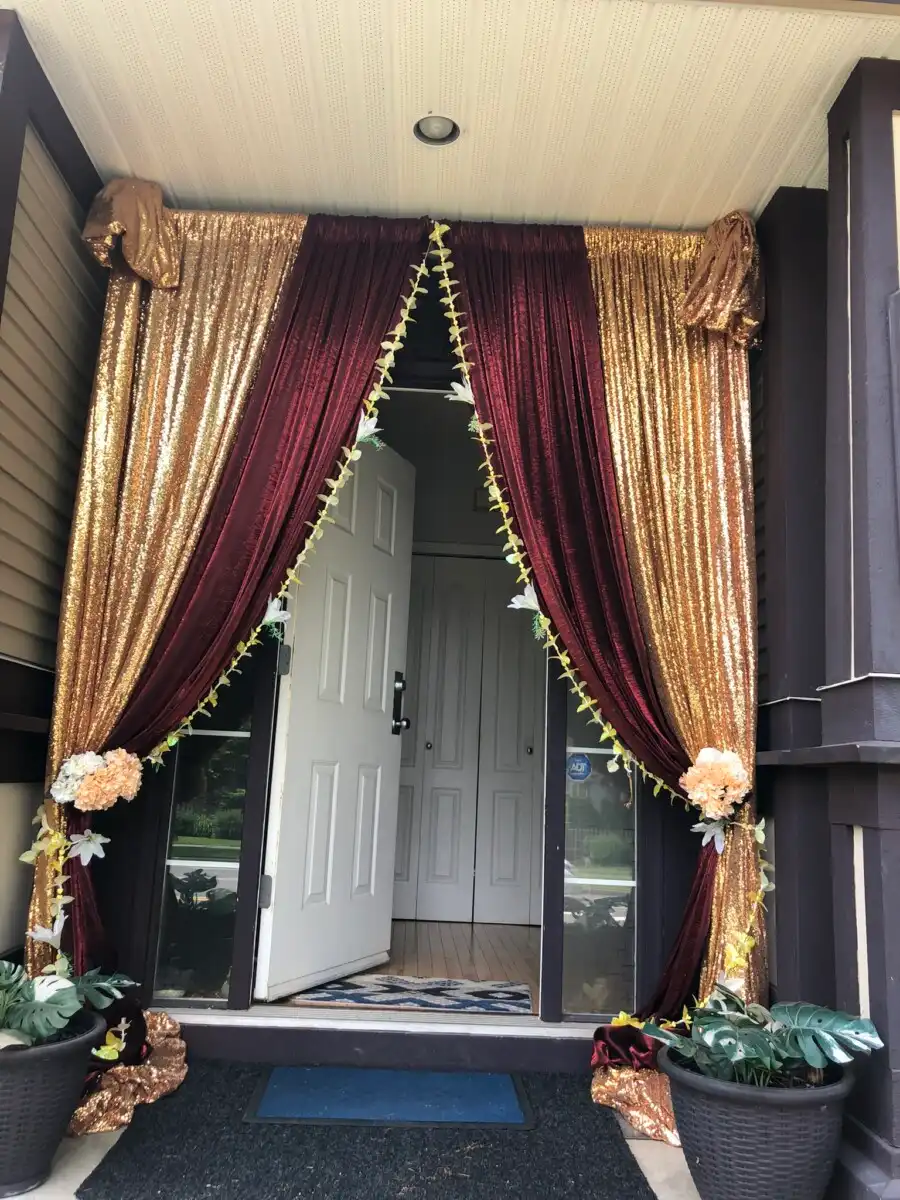 Gold and maroon home entrance drapes with floral garlands · Surrey wedding décor by Dream Decorators