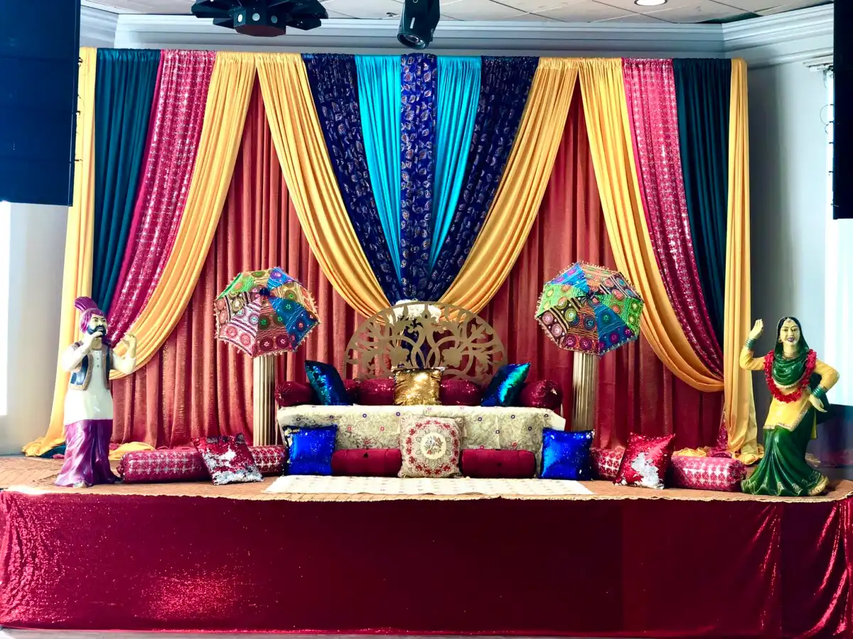 Colourful Punjabi sangeet stage with folk statues and umbrellas · Dream Decorators