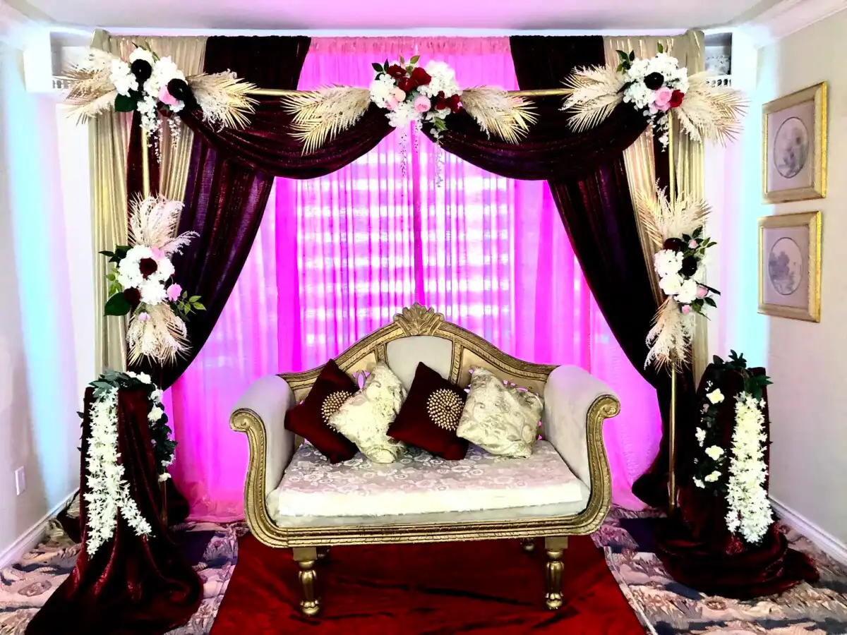 Burgundy and fuchsia reception stage with gold sofa · Dream Decorators