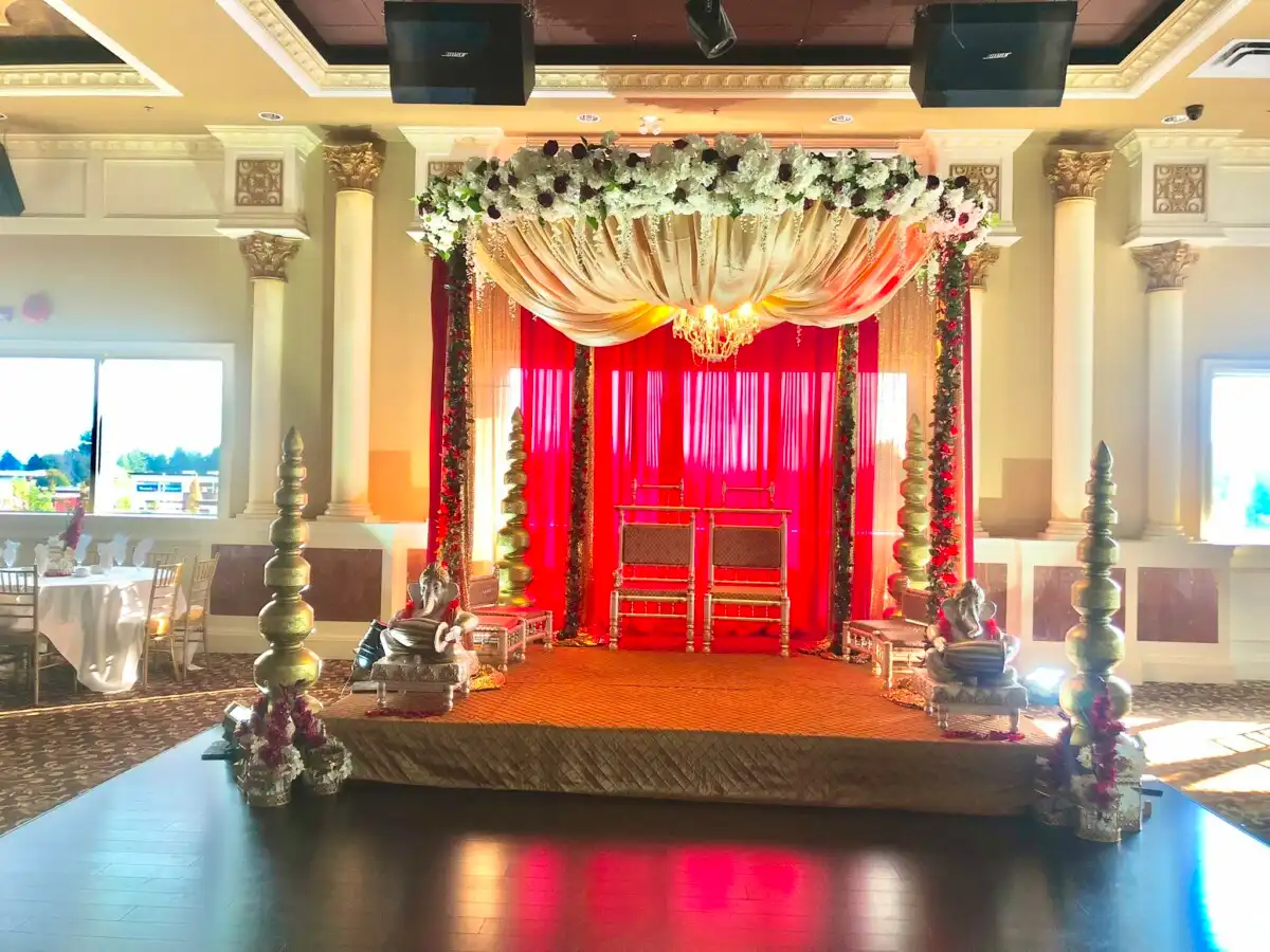Red and cream floral mandap with crystal chandelier · Surrey wedding décor by Dream Decorators