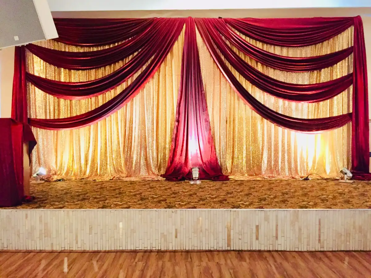 Red and gold sequin wedding stage backdrop with uplighting · Dream Decorators